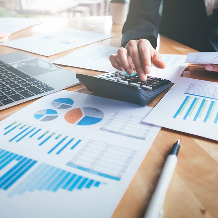 man using a calculator with spreadsheets laid out across the desk